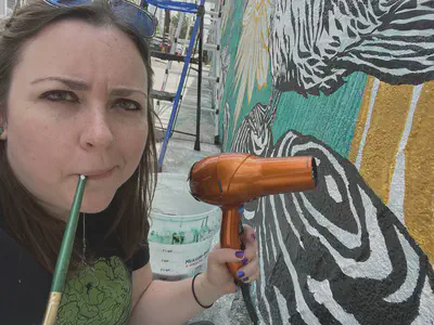 Dr.McAnulty using a blowdryer to speed the mural drying process. Photo by Dr. Sarah McAnulty.